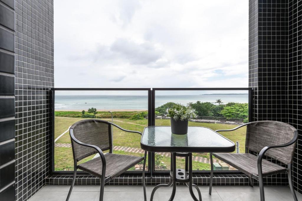 a table and chairs on a balcony with a view of the ocean at Hido Hostel in Kenting