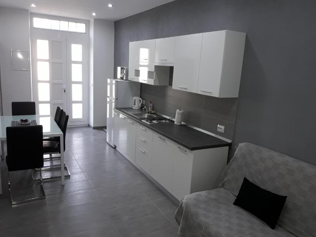 a kitchen with white cabinets and a table and a couch at Apartments Vidulić in Mali Lošinj