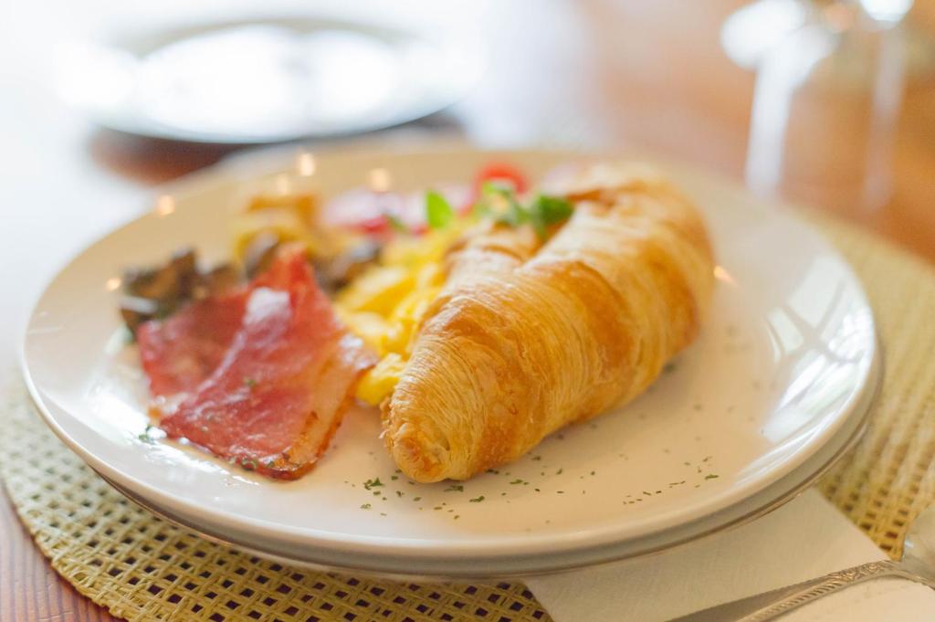 a plate of food with a croissant and bacon at Osborne House in Pretoria