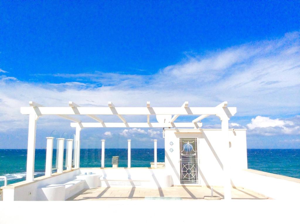 a building on the beach with the ocean in the background at Casa Mare Sole in Villanova di Ostuni