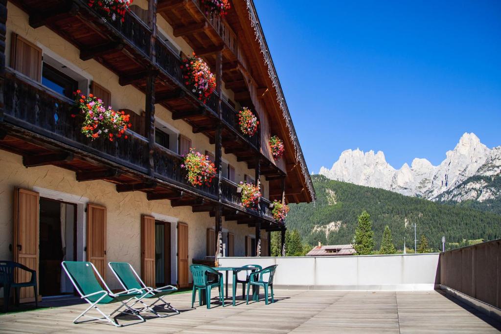 un gruppo di sedie e tavoli su un balcone con vista sulle montagne di Buffaure a Parte a Pozza di Fassa