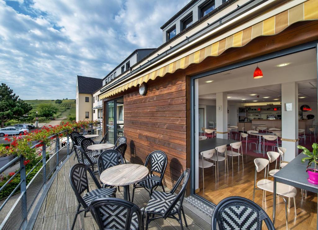 a patio with chairs and tables on a balcony at Hostel - Le Mittel in Mittelwihr