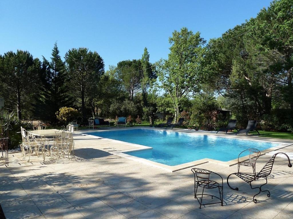 a large swimming pool with chairs and a table at La maison de la Cigale in Forcalqueiret