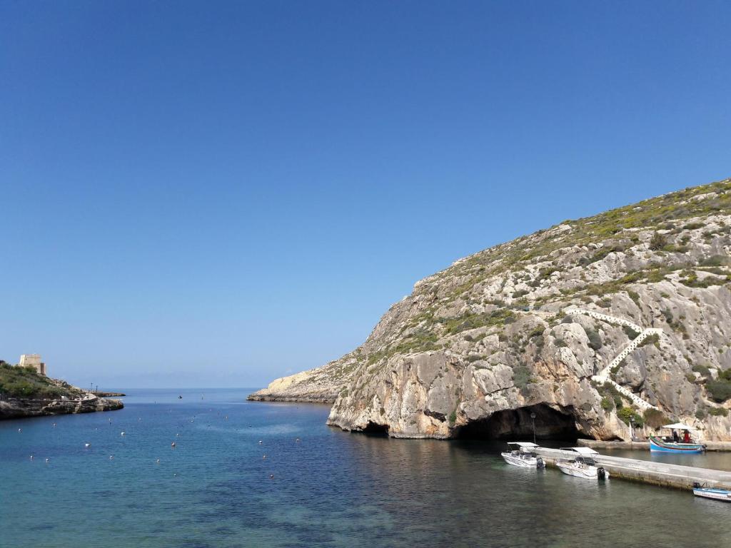 a group of boats in the water next to a cliff at Antros, Apartment 1 in Xlendi