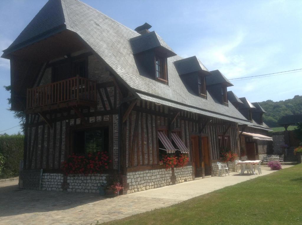 un edificio con techo de gambrel con flores. en Chambres d'Hôtes Le Pressoir, en Saint-Martin-de-Boscherville