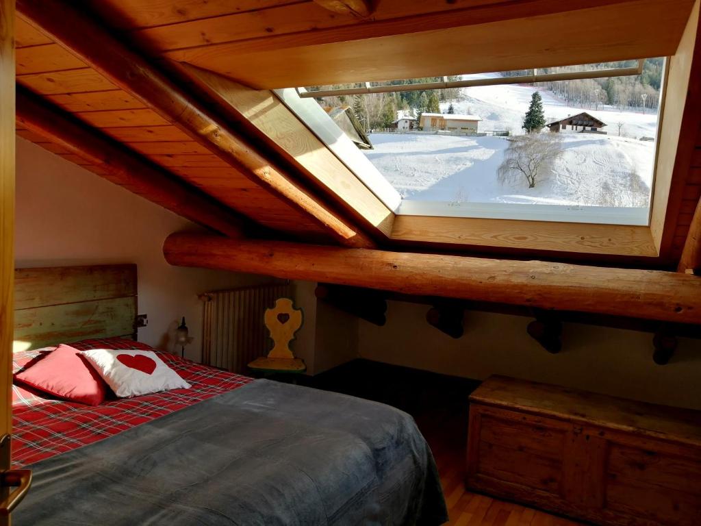 um quarto com uma cama e uma grande janela em Appartamento TEMELIN em Bormio