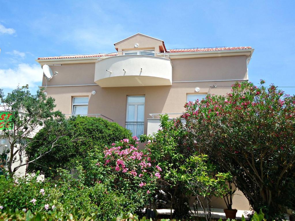 a building with flowering trees in front of it at Apartments Karolina in Novalja