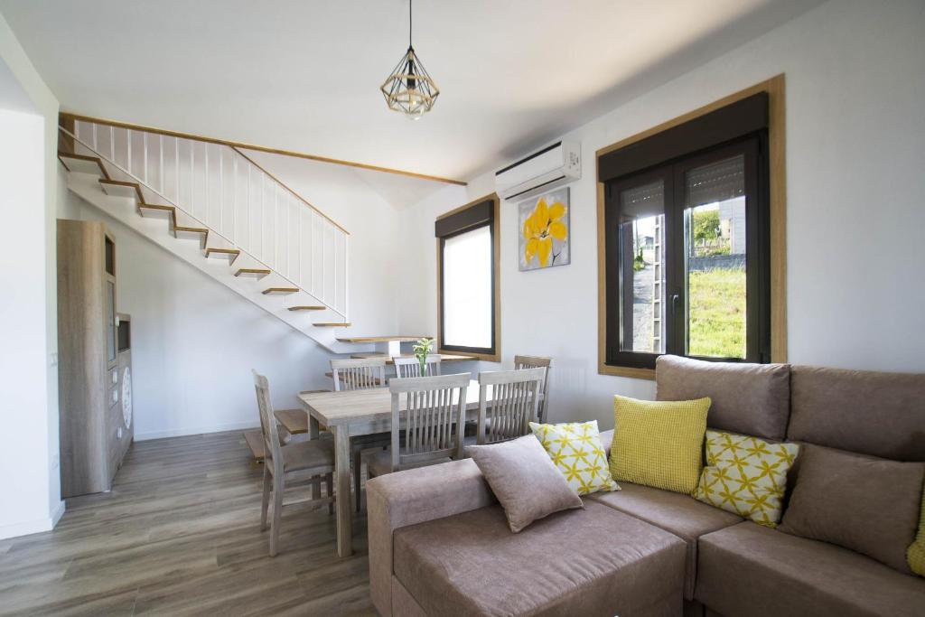 sala de estar con sofá, mesa y escaleras en Casa A Rotea en Vilaboa
