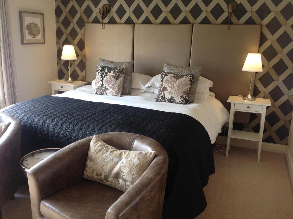 a bedroom with a large bed and two chairs at The Coach House in Hawarden