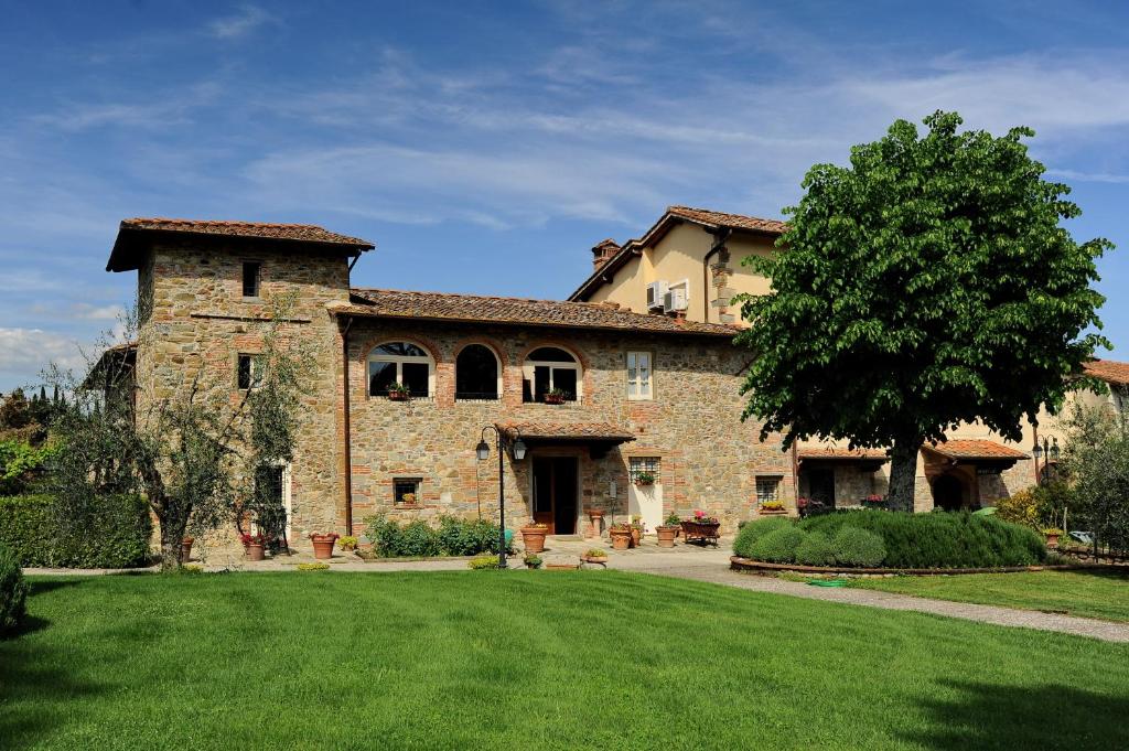 - un grand bâtiment en pierre avec un arbre dans la cour dans l'établissement Erboli Residence, à Cavriglia