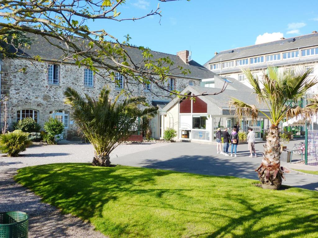 un gruppo di persone che camminano attraverso un cortile con palme di Auberge de Jeunesse Ethic étapes Saint Malo a Saint Malo