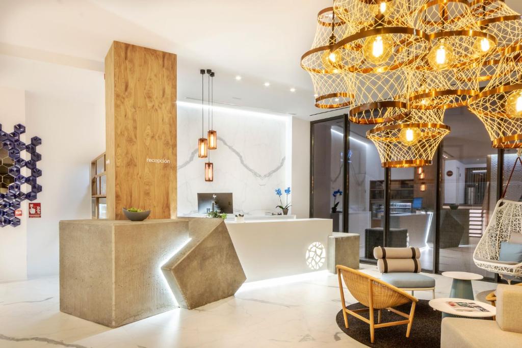 un vestíbulo con una gran lámpara de araña y sillas en Hotel Silgar 92 en Sanxenxo