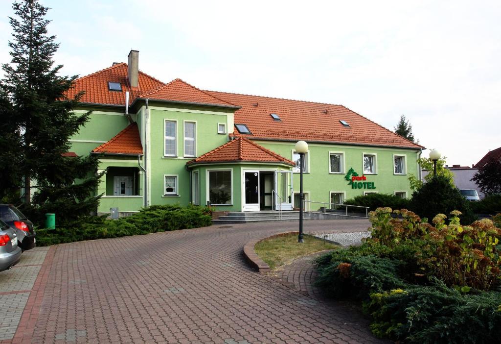 uma casa verde com telhados vermelhos numa estrada de tijolos em Park Hotel em Rzepin