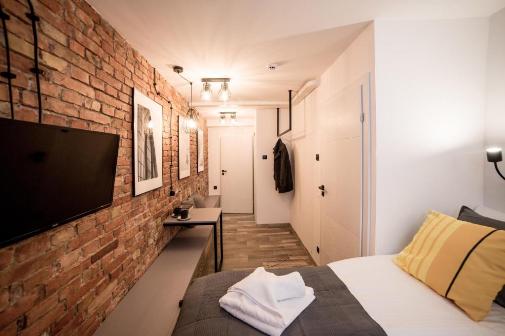 Cette chambre dispose d'un mur en briques, d'un lit et d'une télévision. dans l'établissement UNDERGROUND GDYNIA, à Gdynia