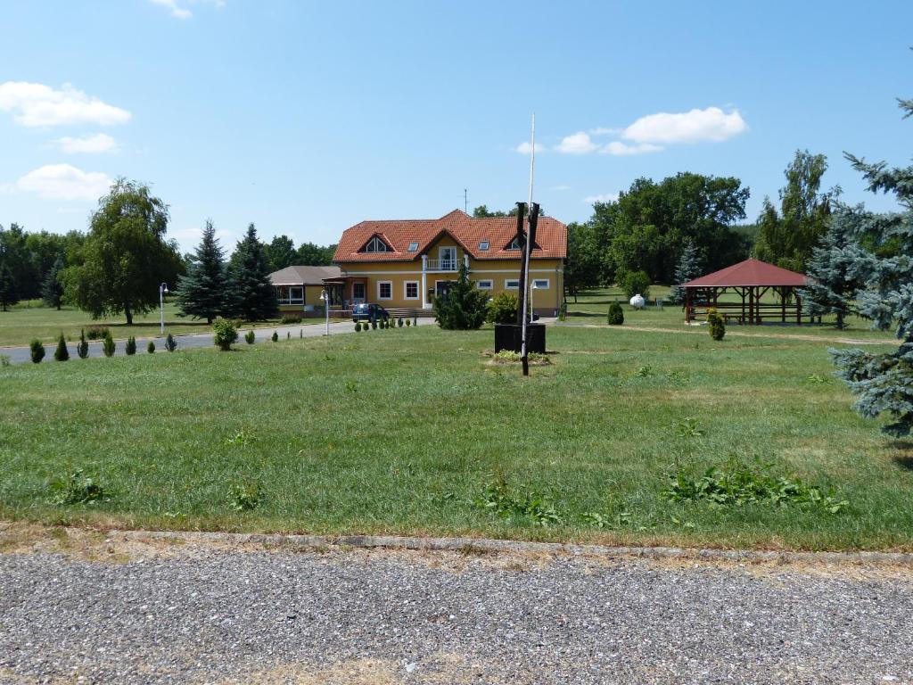 a house in a field with a gazebo at Tó Panzió Őrség Bajànsenye in Bajánsenye