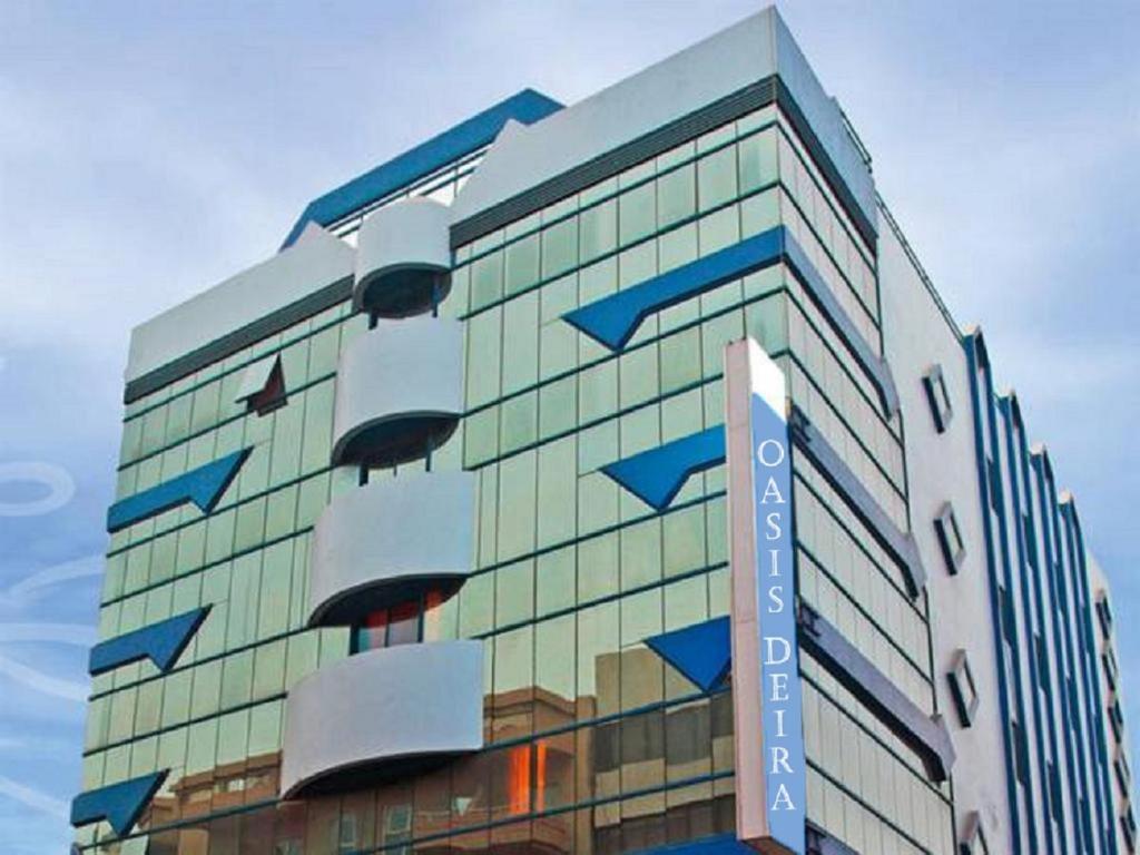 a large glass building with a sign on it at Oasis Deira Hotel in Dubai