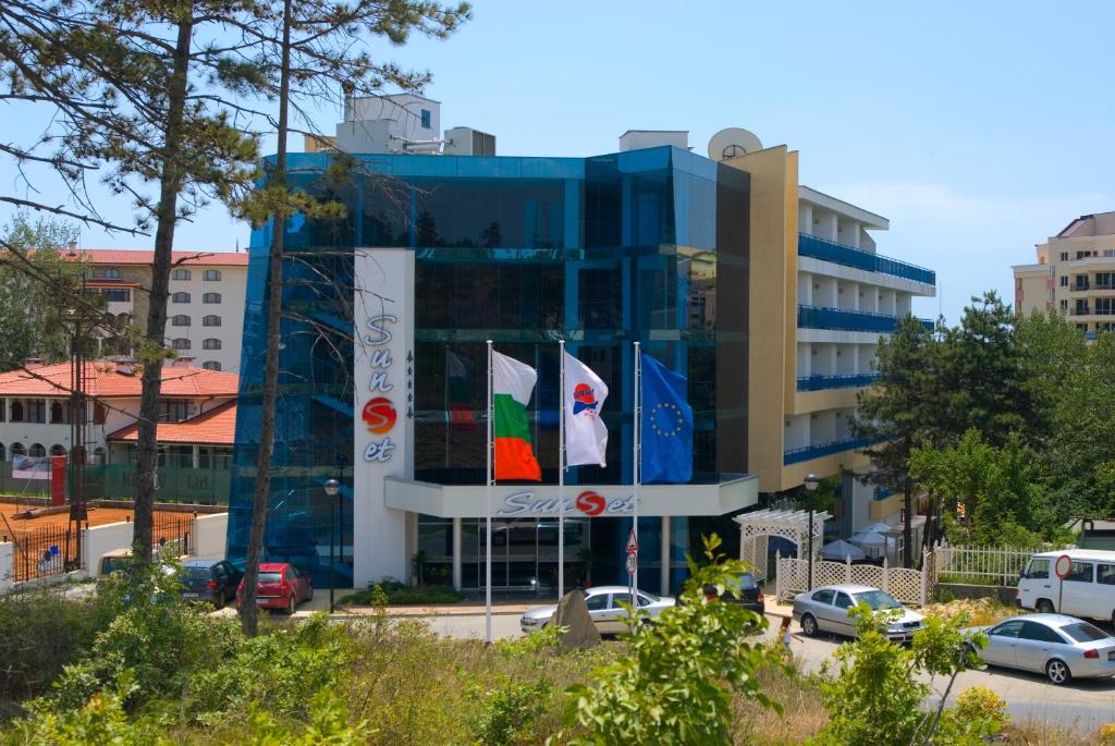 un gran edificio azul con banderas delante en Sunset Hotel - All Inclusive, en Sunny Beach