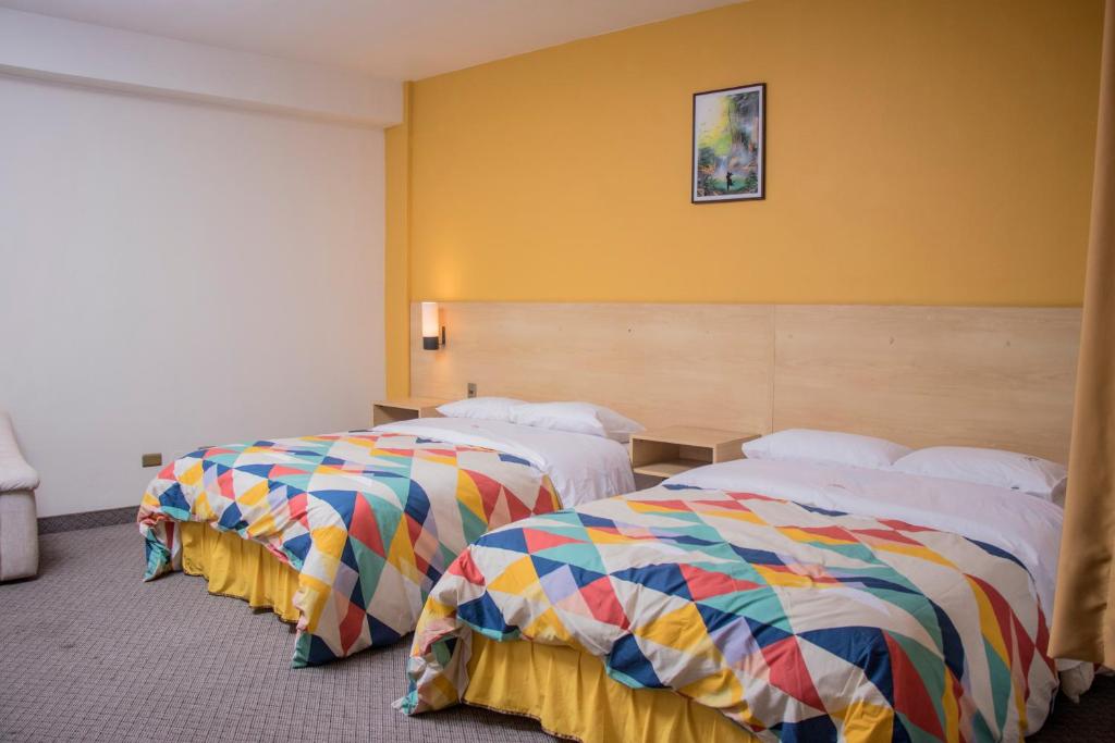2 camas en una habitación de hotel con mantas coloridas en Hotel La Paz, en La Paz