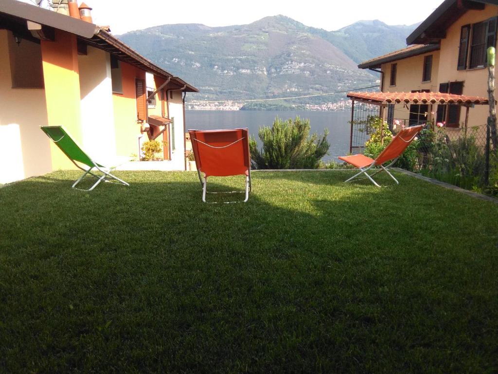 3 Stühle auf einem Rasen neben einem Haus in der Unterkunft La Mansarda sul Lago in Lezzeno