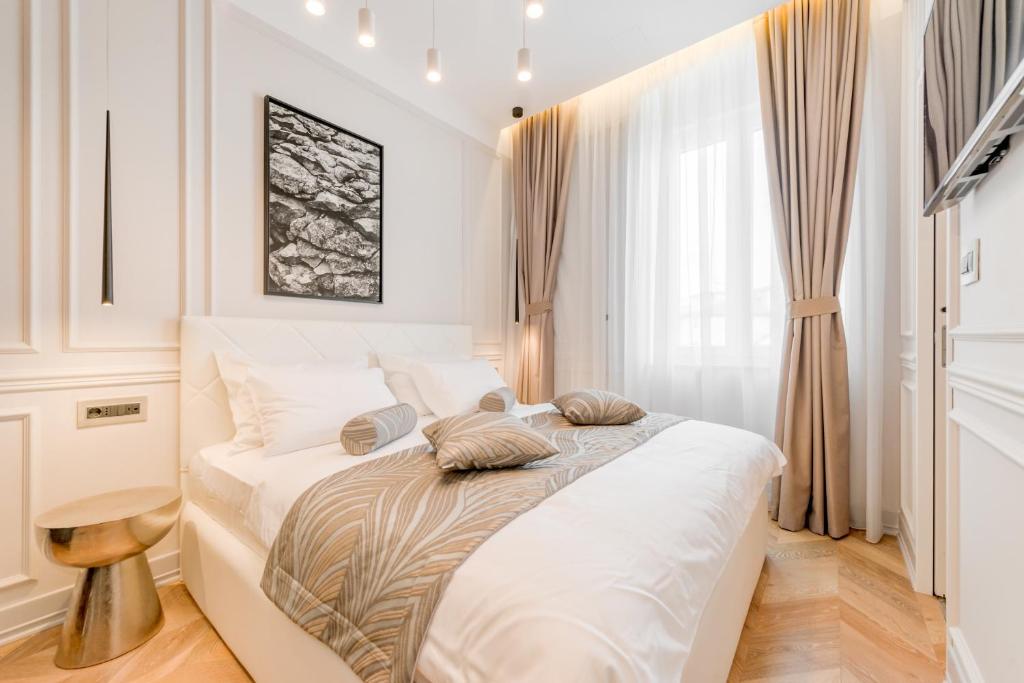 a bedroom with a large white bed with pillows on it at Luxury Rooms L'Avenue Split in Split