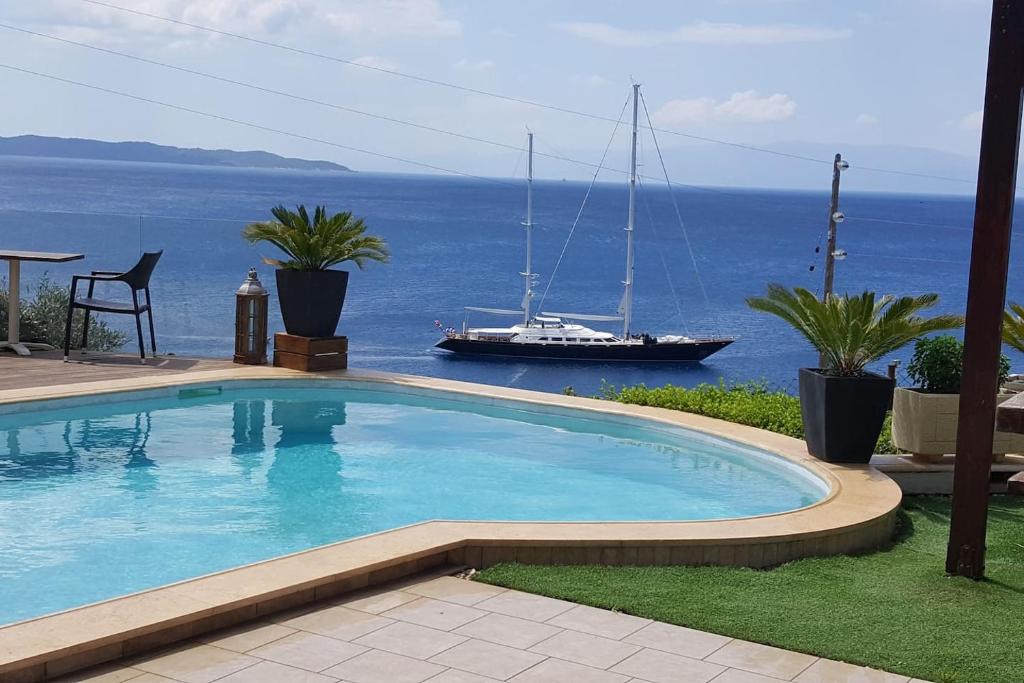 a large swimming pool with a boat in the ocean at Villa Vasi in Porto Heli