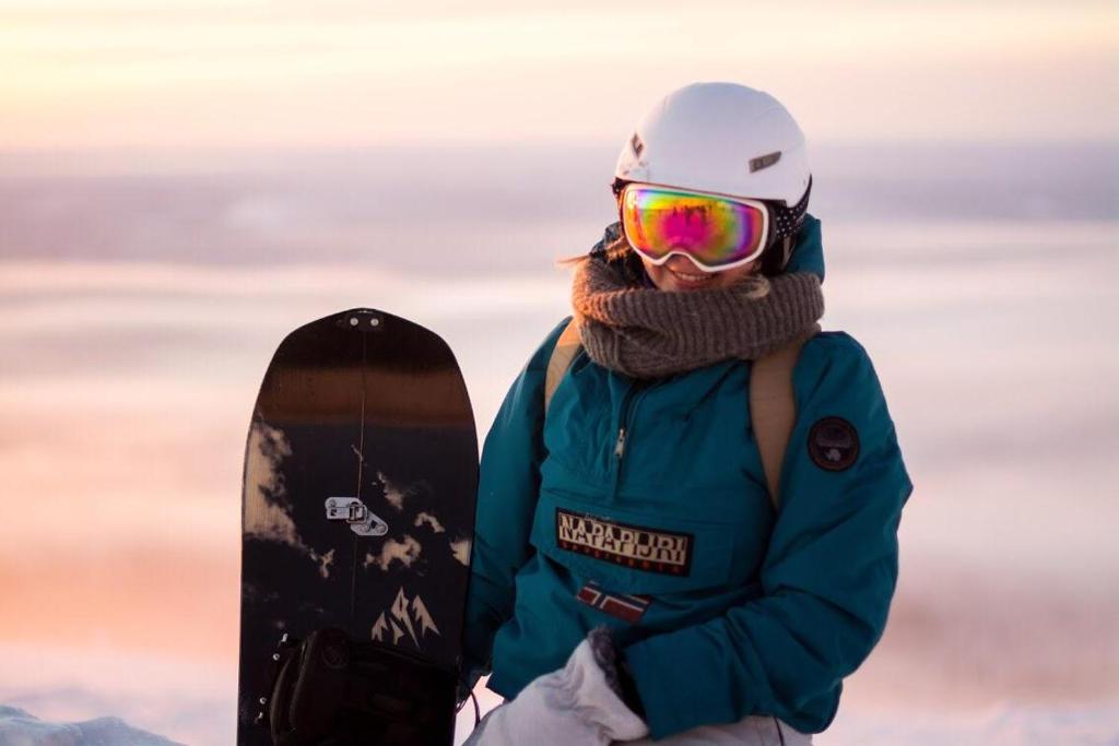 Una donna che tiene uno snowboard in cima a una montagna di Kuerkievari KuerHostel ad Äkäslompolo