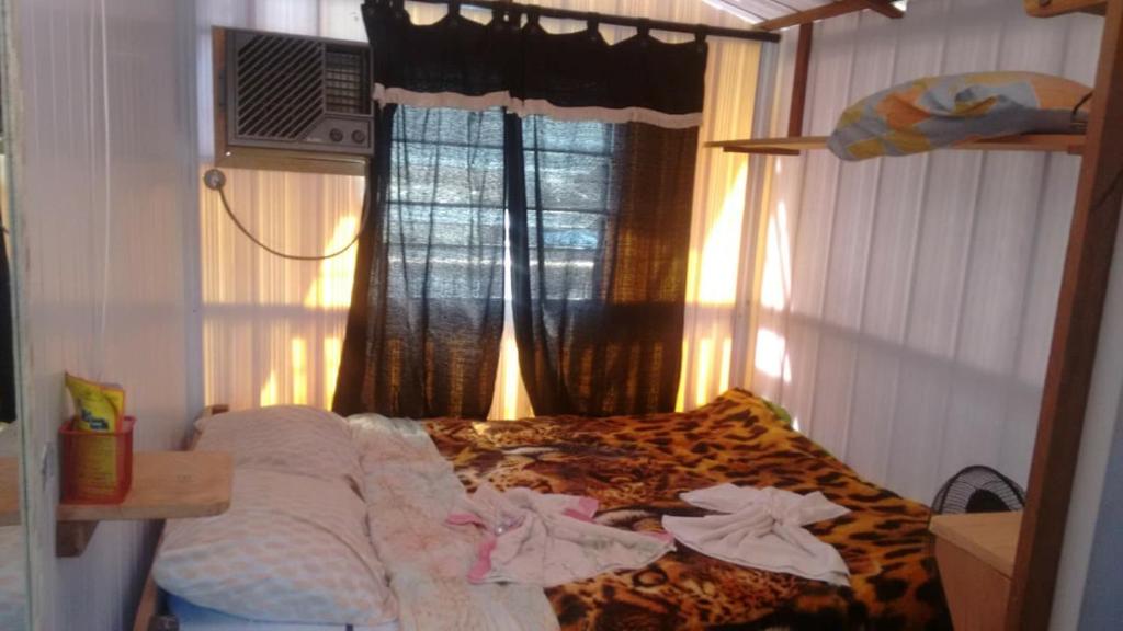 a bedroom with a bed and a window with towels at Pousadinha da LIZA E HOSTEL in Mangaratiba