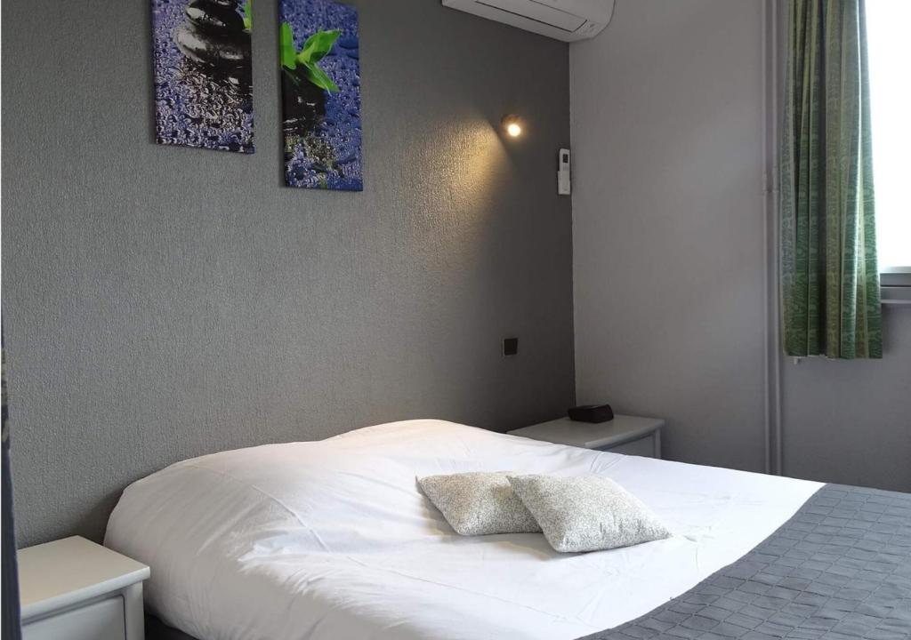 een slaapkamer met een wit bed met 2 kussens erop bij Europa Hotel in Roussillon en Isere