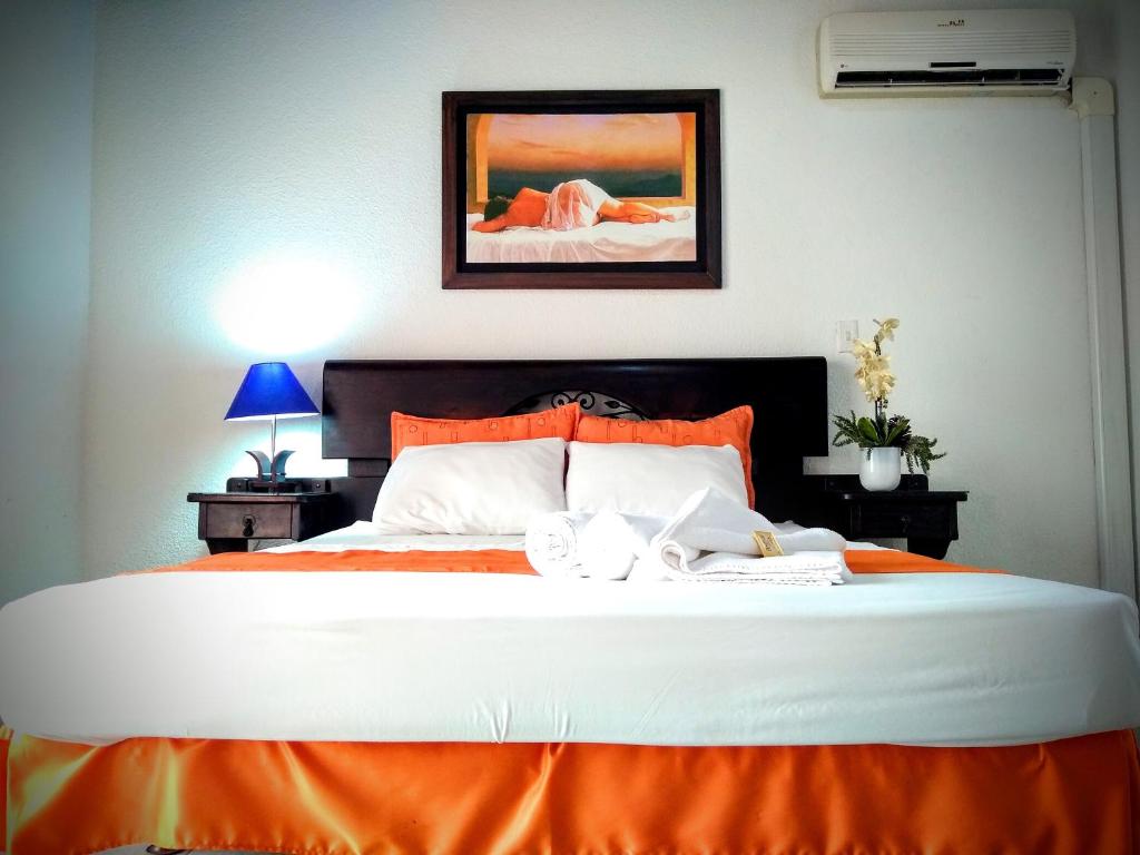 a bedroom with a large bed with an orange blanket at Hotel el Atajo in Yopal