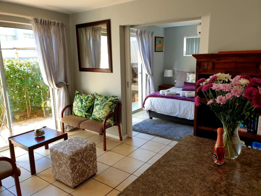 een woonkamer met een bed en een vaas met bloemen bij D'urban Ridge Self catering Apartment in Kaapstad