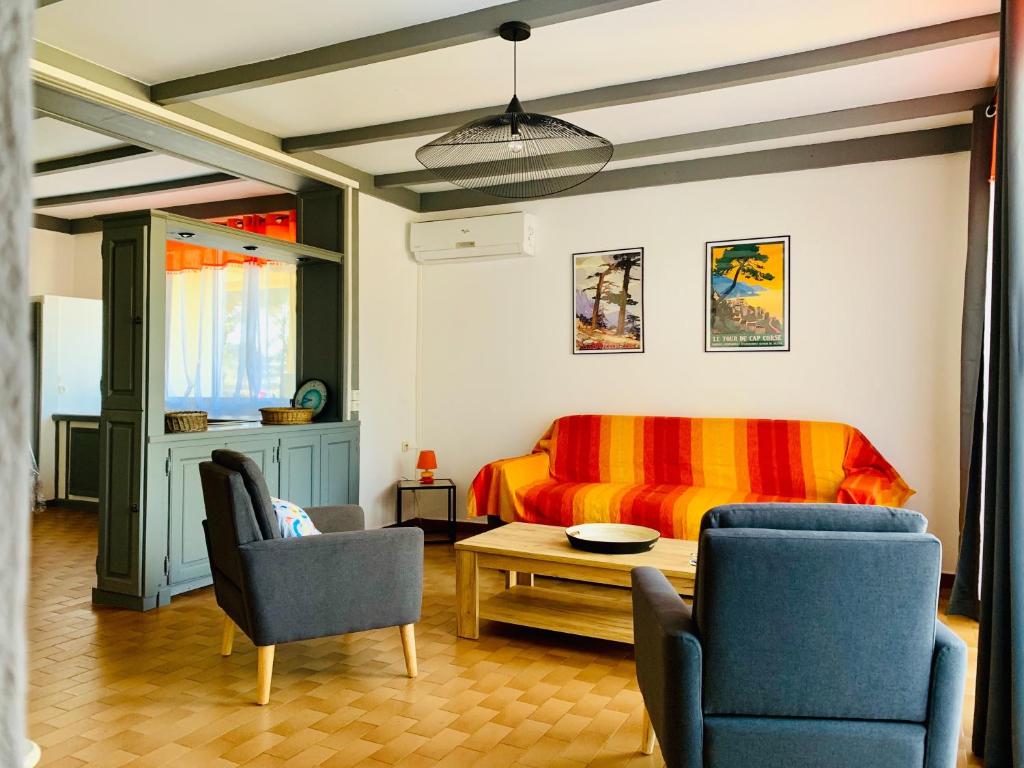 een slaapkamer met een bed en 2 stoelen en een tafel bij Bungalows Filippi in Porto-Vecchio