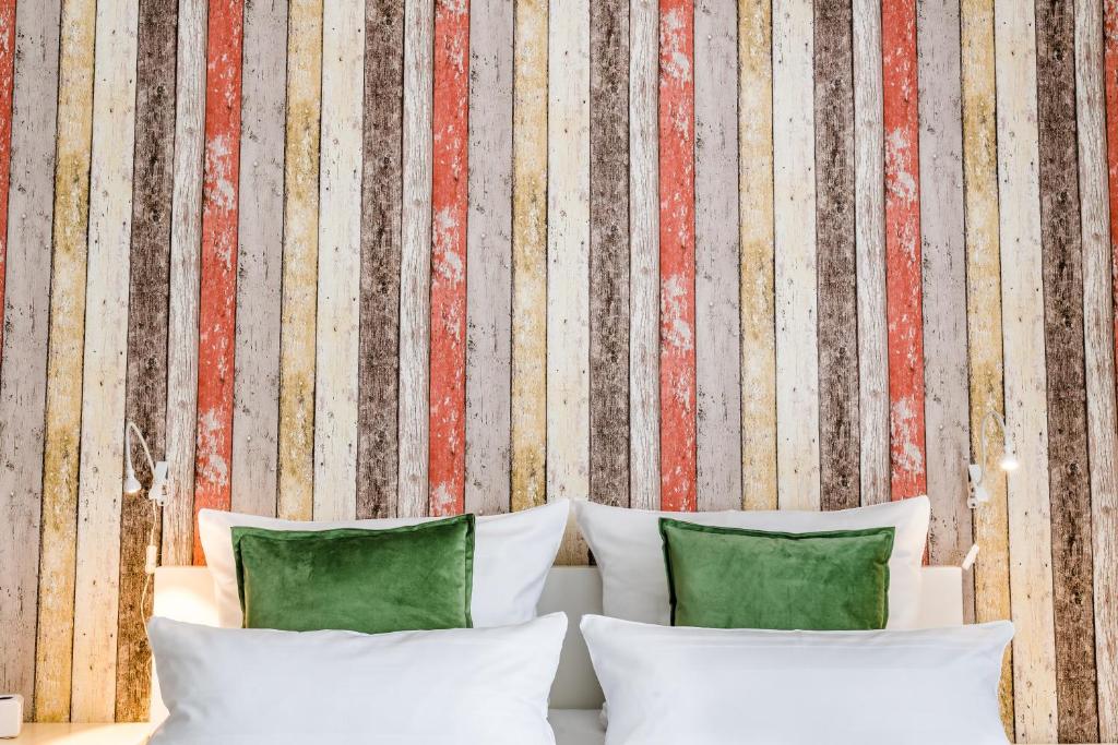 1 cama con almohadas blancas frente a una pared a rayas en Haus am Park - Ihr Gästehaus in Velbert, en Velbert