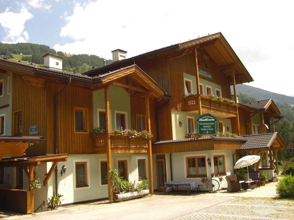 un grande edificio in legno con una panca di fronte di Ferienhäuser Thalbach a Heiligenblut