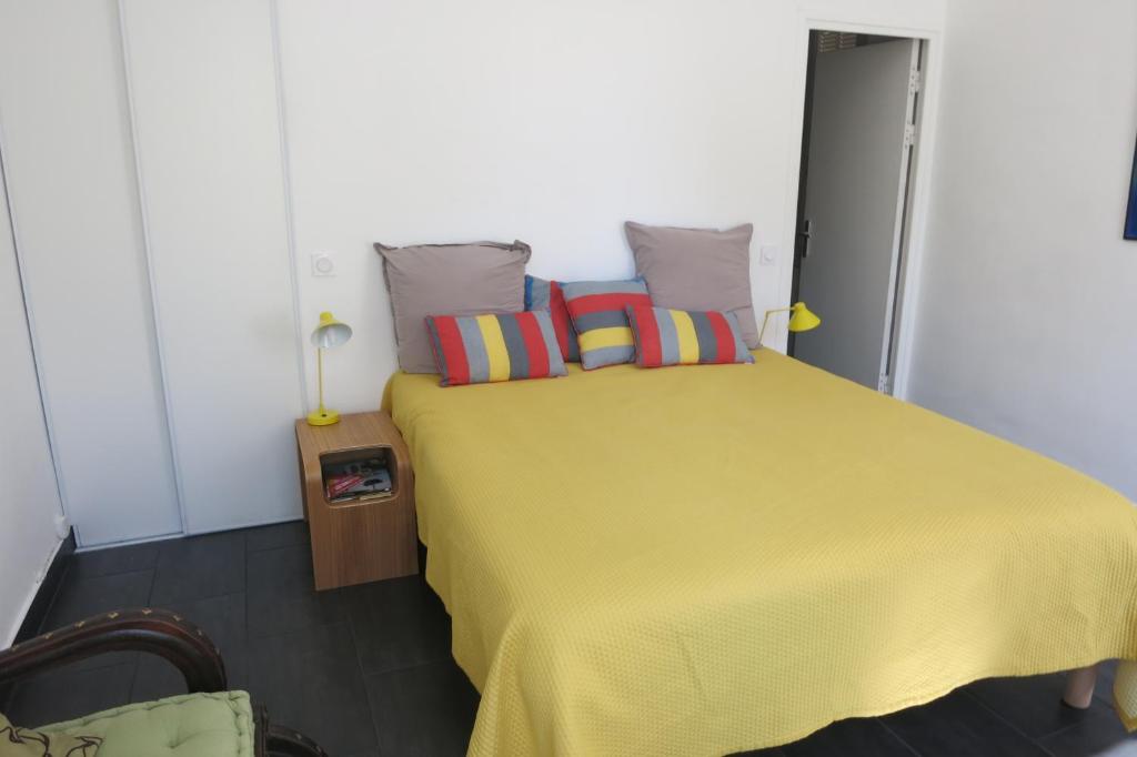 ein Schlafzimmer mit einem gelben Bett und bunten Kissen in der Unterkunft Villa les Lys in La Seyne-sur-Mer