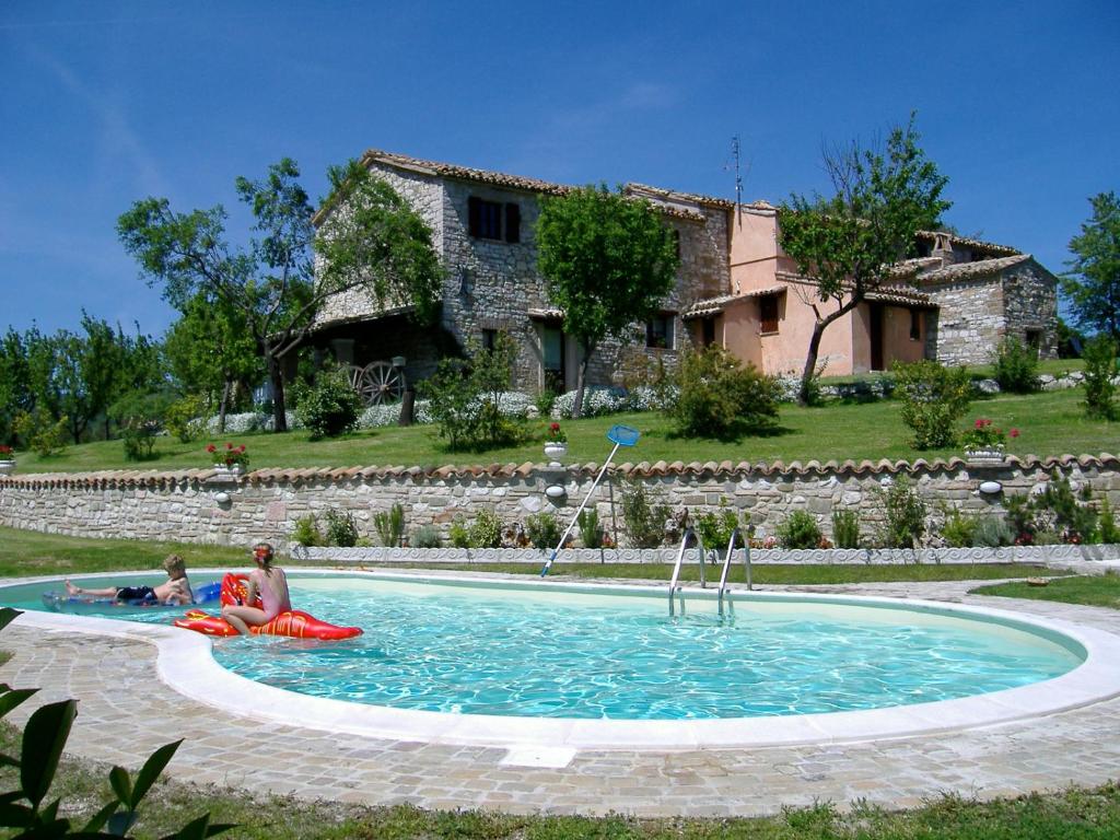 dos personas sentadas en una piscina frente a una casa en La collina dei ciliegi, en Cagli