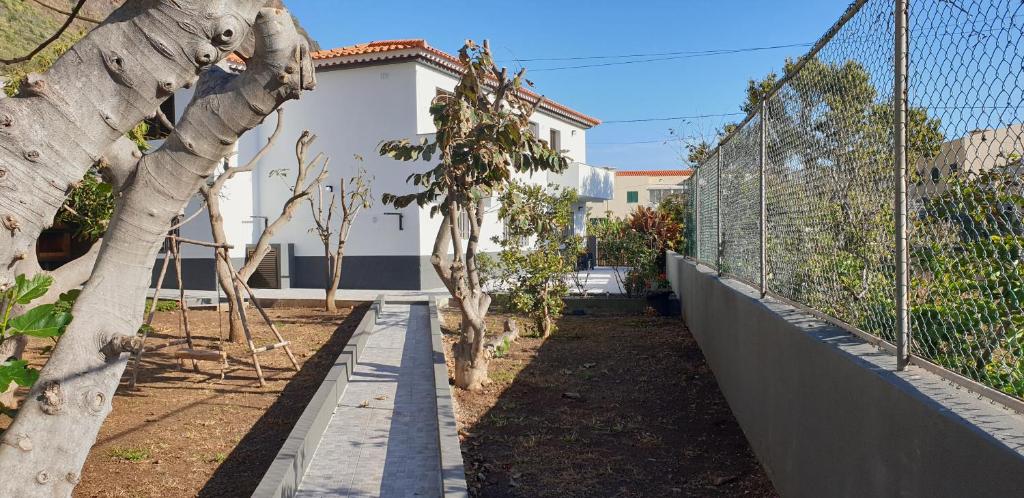 a garden with a fence and trees and a building at Casa da Lagoa in Calheta