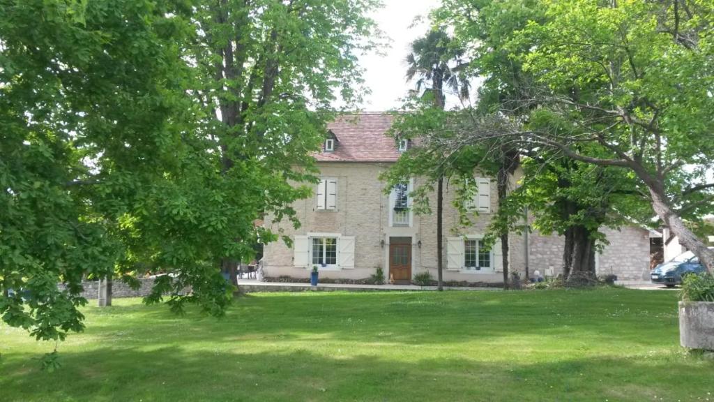 a large stone house with trees in the yard at Maison COMAYOU in Loubieng