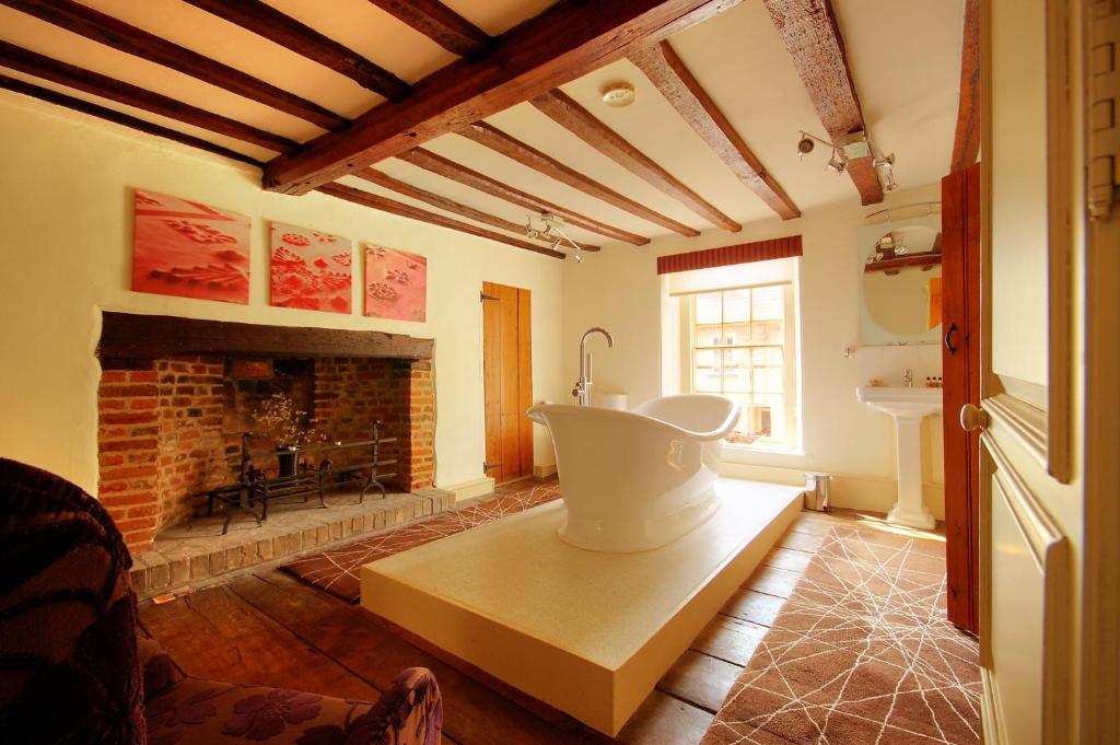 a living room with a fireplace and a bath tub at Sutherland House in Southwold