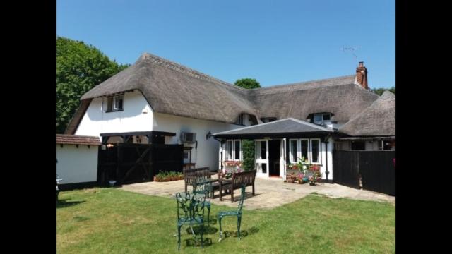 uma grande casa branca com telhado de palha em White Horse Inn em Andover