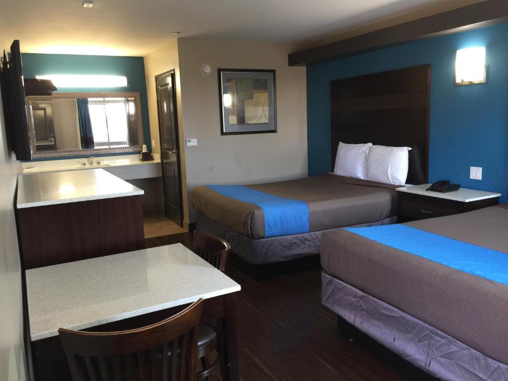 a hotel room with two beds and a table at Crystal Palace Inn in Maywood