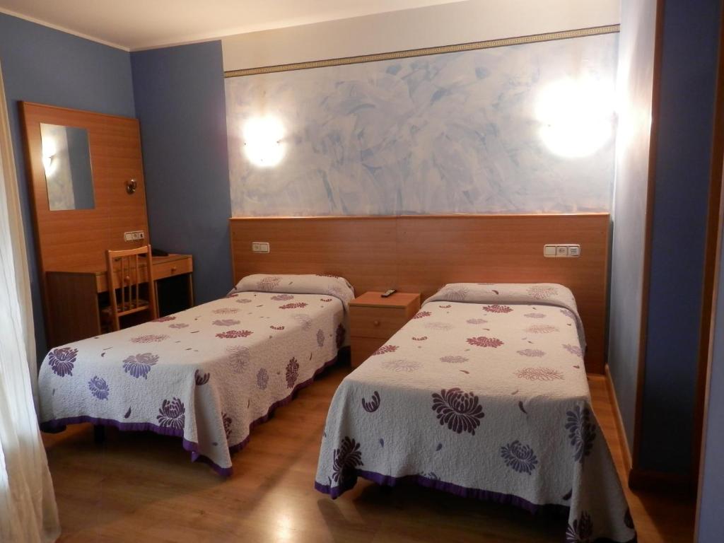 ヒホンにあるHotel Doña Mariaのベッド2台が備わる客室で、壁には絵画が飾られています。