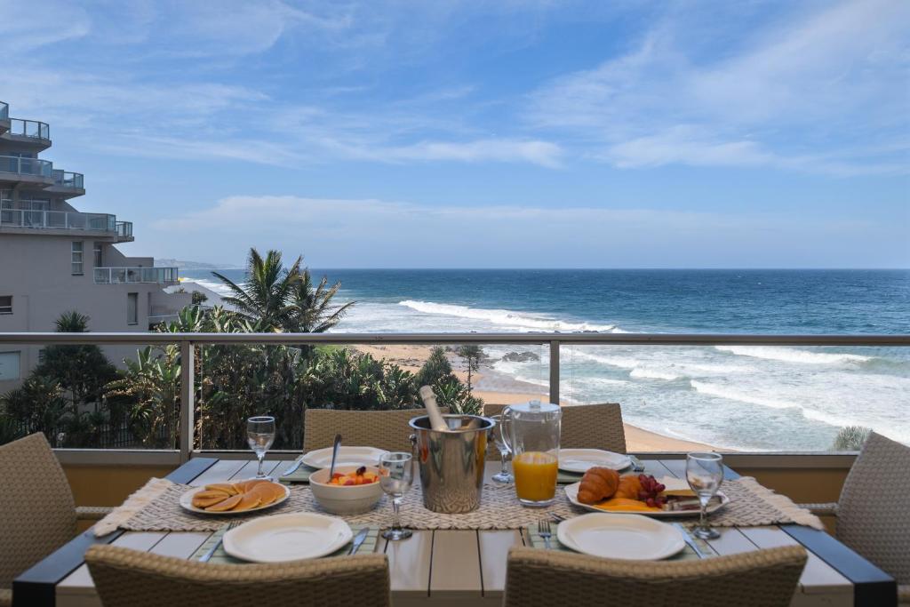 einen Tisch mit Speisen und Meerblick in der Unterkunft Sands Beach Breaks Luxury Beach Front Ballito in Ballito