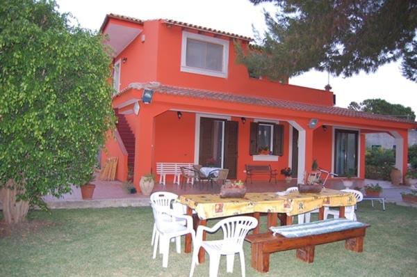 una casa naranja con una mesa y sillas frente a ella en Villa Marco Polo, en Fanusa