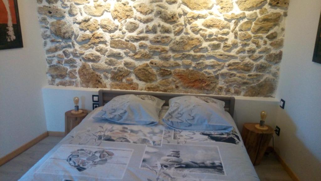 Cama en habitación con pared de piedra en Le gite au tilleul en Vauhallan