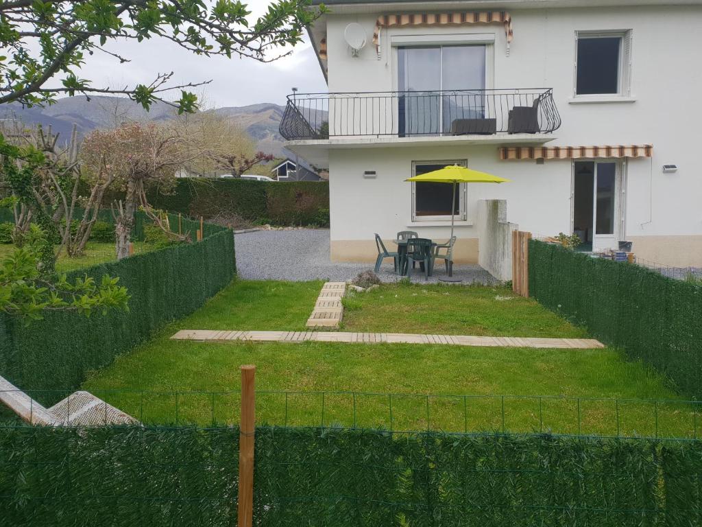 a house with a patio with a table and a yellow umbrella at appartement Isabelle in Lau-Balagnas