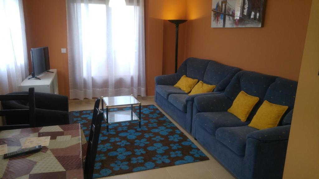 een woonkamer met een blauwe bank en gele kussens bij SMR As Pasadas in San Pedro de Benquerencia