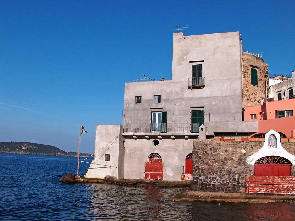 a building sitting in the water next to a body of water at Apartment Lo Scuopolo-2 by Interhome in Ischia