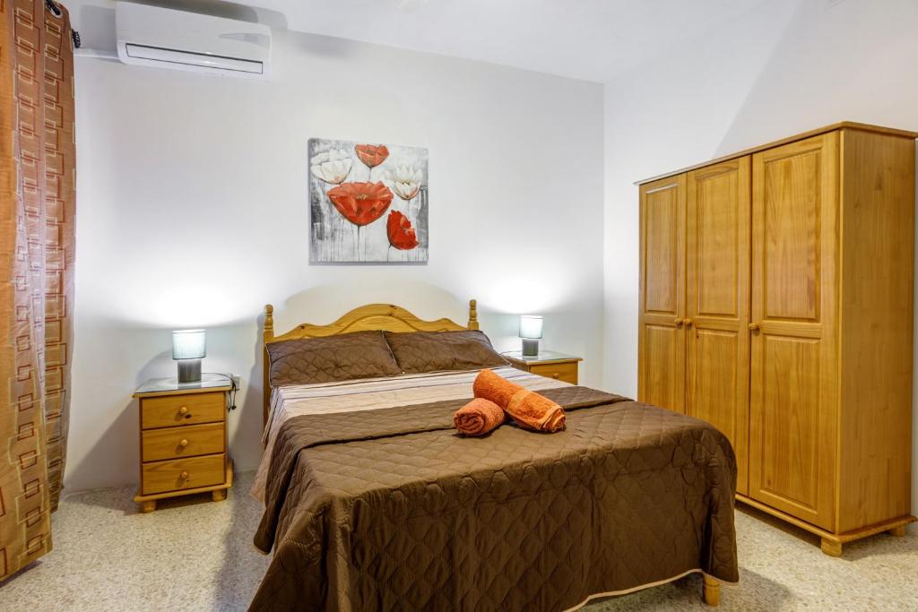 1 dormitorio con 1 cama y armario de madera en Dolphin Court, en Marsalforn