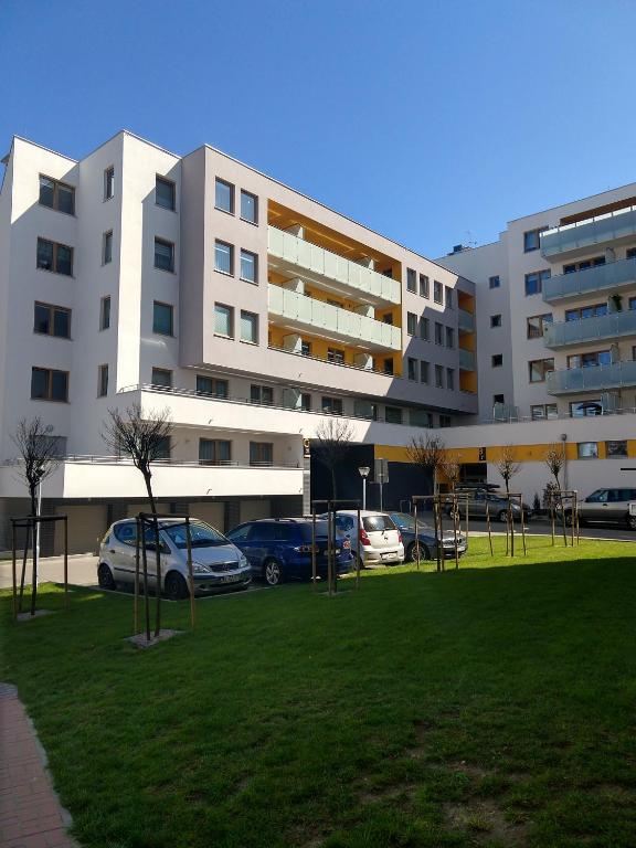duży biały budynek z samochodami zaparkowanymi w parku w obiekcie Apartament FALA-Miodowy Dom w Kołobrzegu