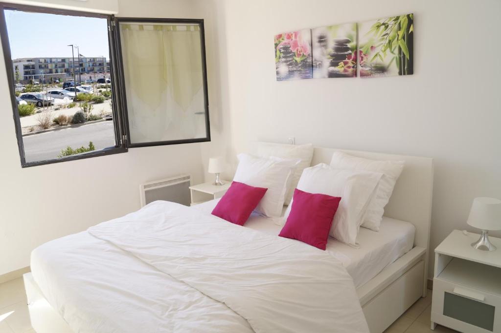 - une chambre avec un lit blanc et 2 oreillers roses dans l'établissement Cittazen Aix-en-Provence - Entre gare TGV et centre ville, calme et confort moderne, à Aix-en-Provence
